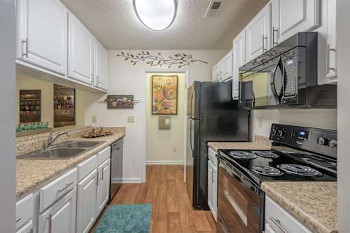 A kitchen with black appliances and white cabinets.