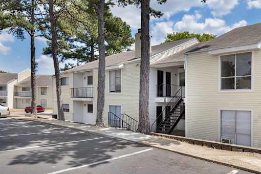 A row of apartment buildings with trees in front.