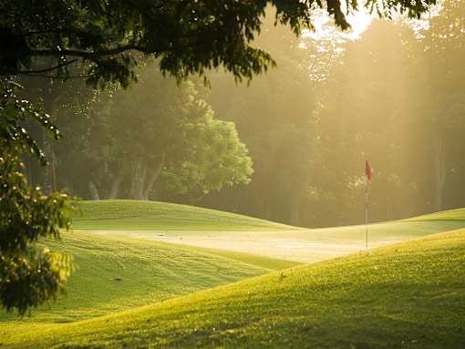 A golf course with a red flag on the green.