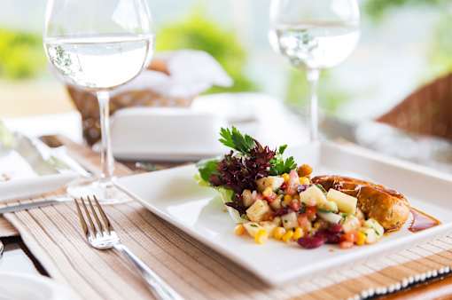 A white plate with a salad and a piece of meat on it.