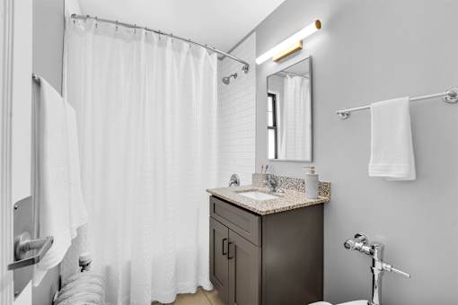 A bathroom with a sink, mirror, and shower curtain.