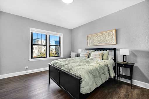 A bedroom with a large bed and a window overlooking a cityscape.