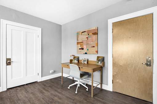 A room with a desk and a chair in front of a wooden door.