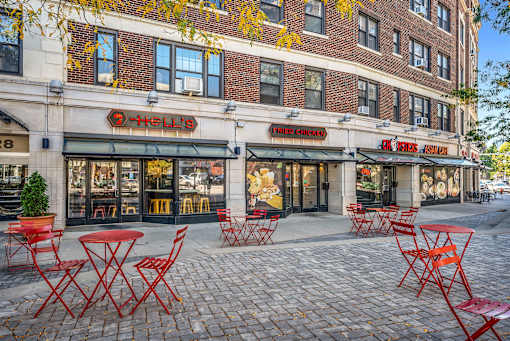 A restaurant with red chairs and tables outside.