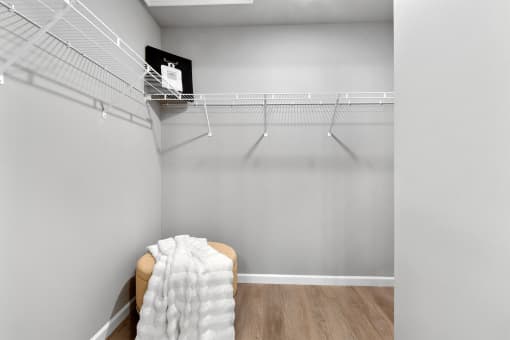 an empty closet with a chair and a wire rack on the wall