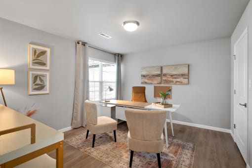 a home office with a desk and chairs and a window