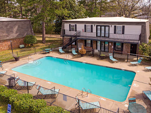 A small pool surrounded by a black fence and chairs.