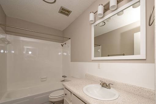 A bathroom with a white toilet, sink, and mirror.