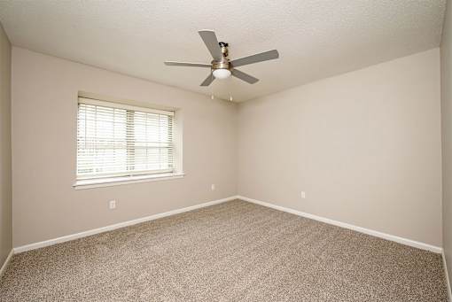 A room with a ceiling fan and a window with blinds.