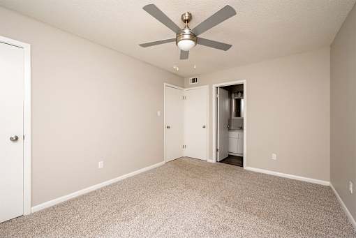 A room with a ceiling fan and carpeted floor.