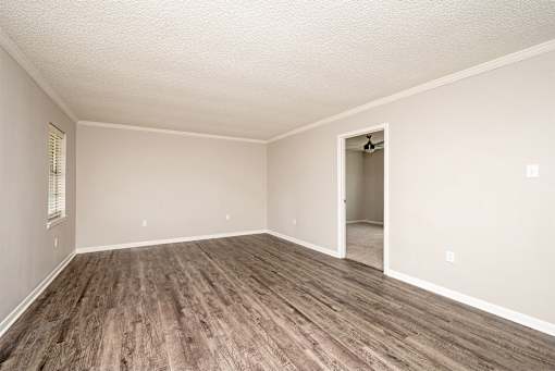 A room with a wooden floor and a doorway leading to another room.