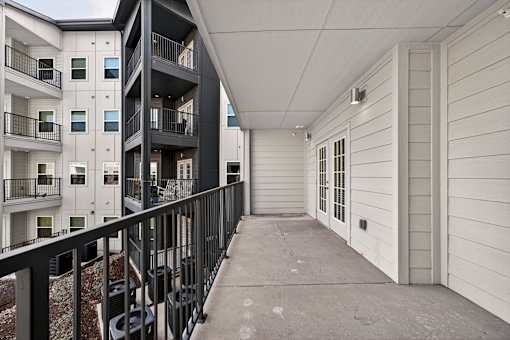 A long hallway with a black railing and white walls.