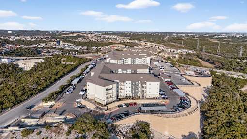 An aerial view of a parking lot with cars and a building in the background.