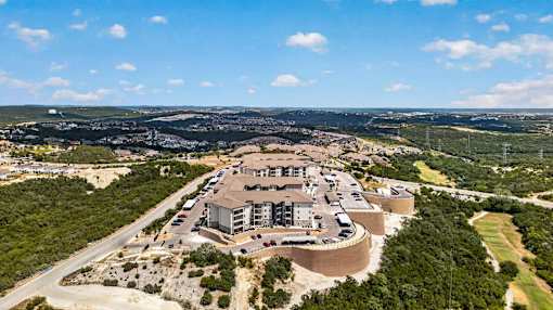 An aerial view of a large industrial facility surrounded by greenery and a road.