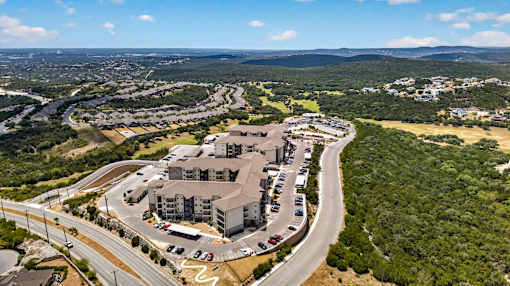 A large building complex is surrounded by a parking lot and a road.