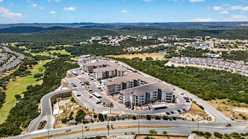 A large building complex is surrounded by a parking lot and roads.