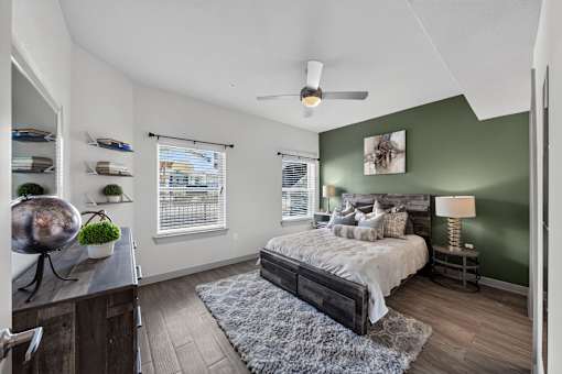 A bedroom with a bed, a ceiling fan, and a window with blinds.