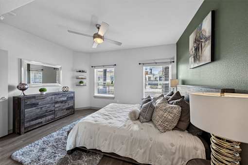 A bedroom with a bed, dresser, and ceiling fan.