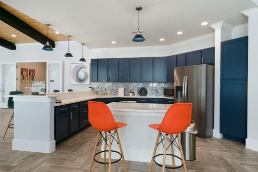 a kitchen with dark blue cabinets and two orange chairs