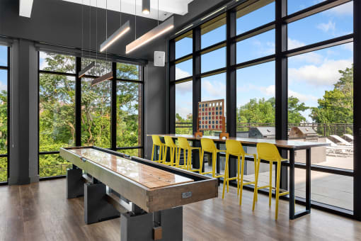 a games room with a shuffleboard table and yellow bar stools