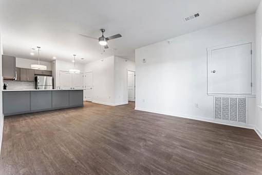 A spacious room with a kitchen area and a ceiling fan.