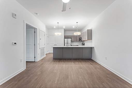 A kitchen with a white wall and a wooden floor.