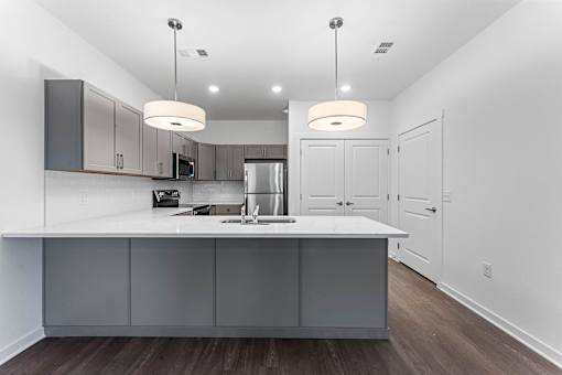 A modern kitchen with a white countertop and grey cabinets.