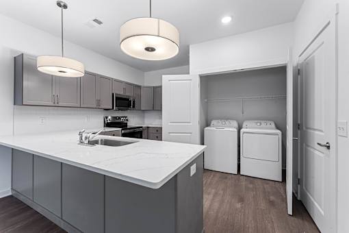 A modern kitchen with a white countertop and grey cabinets.