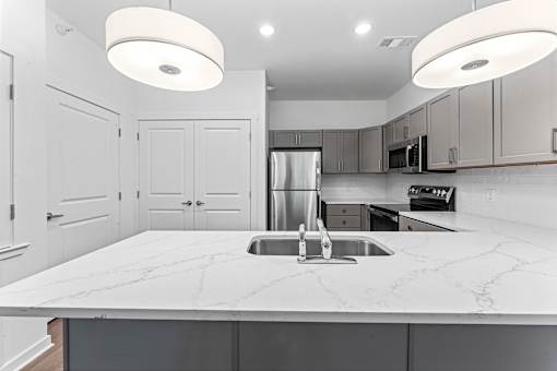 A modern kitchen with a marble countertop and stainless steel appliances.