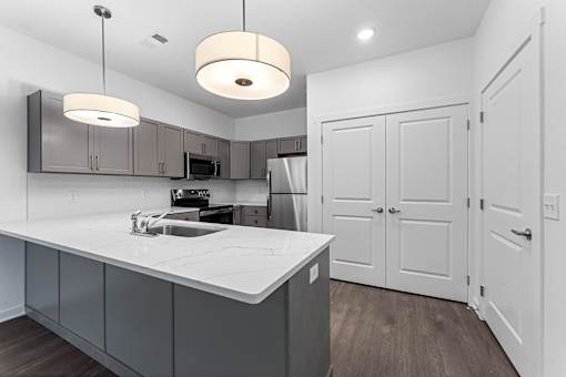 A modern kitchen with a white countertop and grey cabinets.