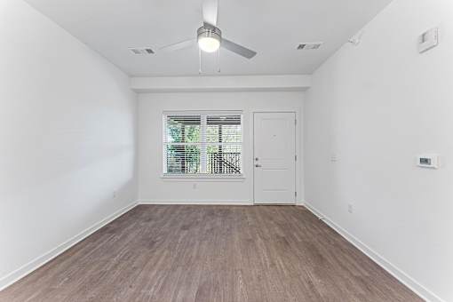 A room with a ceiling fan and a window with blinds.