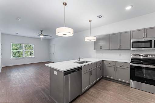 A modern kitchen with stainless steel appliances and wooden flooring.