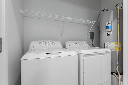Two white washing machines in a small laundry room.