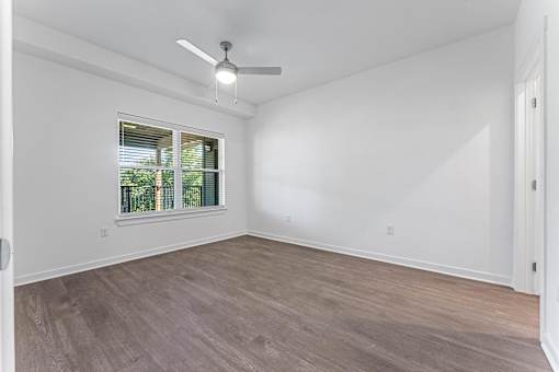 A room with a ceiling fan and a window with blinds.