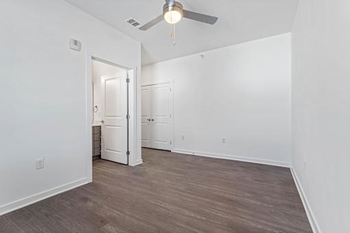 A room with a ceiling fan and wooden flooring.