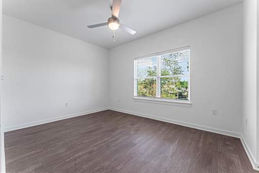 A room with a ceiling fan and a window with blinds.