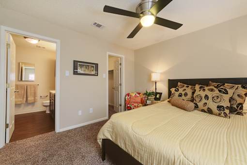 A bedroom with a bed, pillows, and a ceiling fan.