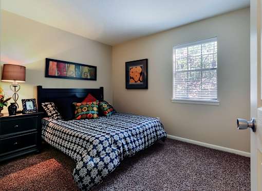 A bedroom with a bed, dresser, and window.