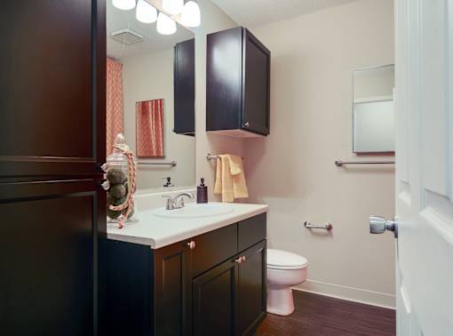 A bathroom with a toilet, sink, and cabinets.