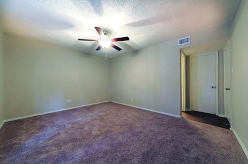A room with a ceiling fan and carpeted floor.