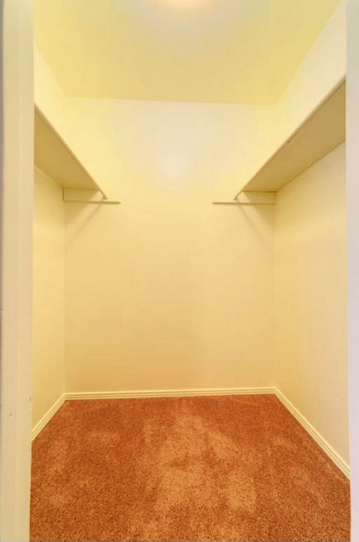 A hallway with a carpeted floor and white walls.