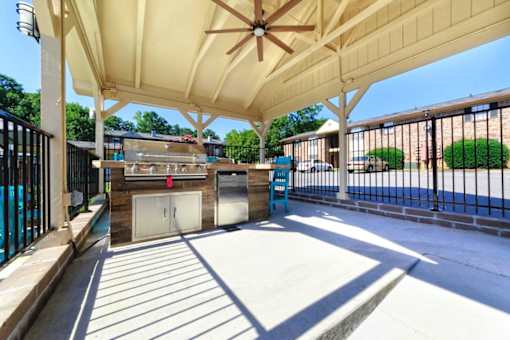 A covered walkway with a ceiling fan and a pool in the background.