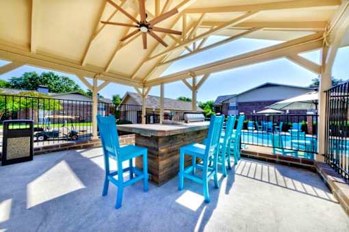 A patio with blue chairs and a table under a canopy.