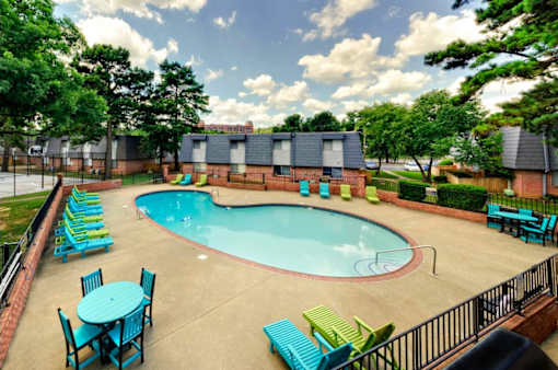 A pool surrounded by chairs and tables.