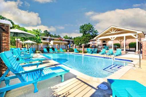 A pool area with blue chairs and a white pavilion.