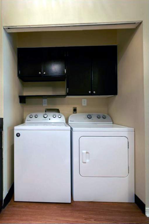 Two white washing machines in a small laundry room.