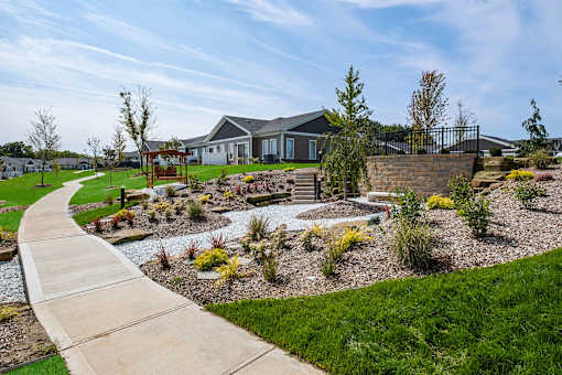 A residential area with a house, a garden, and a paved walkway.