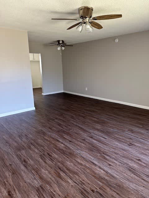 an empty living room with a ceiling fan