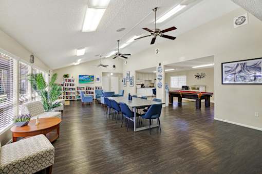 A room with a ceiling fan and a dining table with chairs.