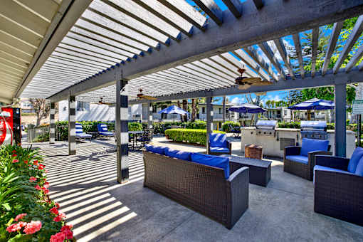 A patio with a white roof and blue chairs.